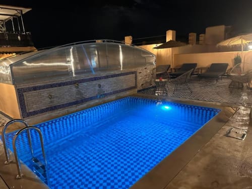 Piscine illuminée sur le toit la nuit avec éclairage bleu au Riad Dar Tahri à Fès, Maroc