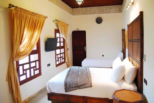 Chambre double standard au Riad Fes Aicha à Fès, avec literie blanche, décor marocain traditionnel, rideaux dorés et boiseries sculptées