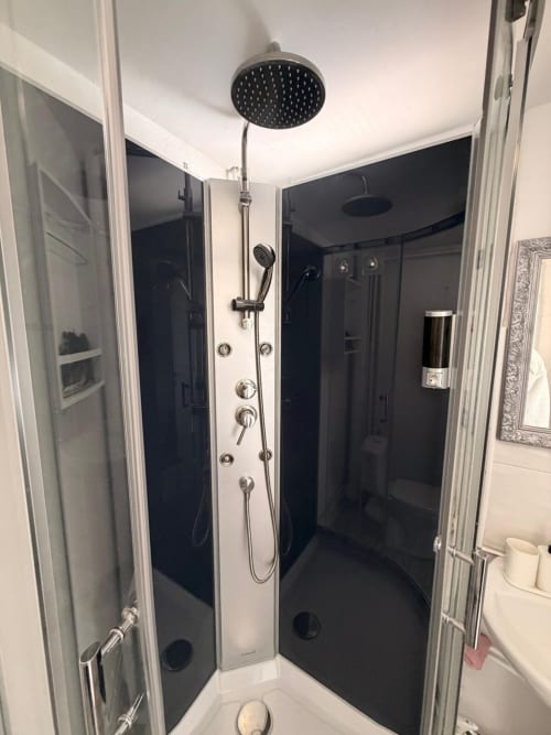 Douche moderne en noir et blanc avec pomme de douche pluie et douchette à main dans l'appartement Kawichimmo Louvres