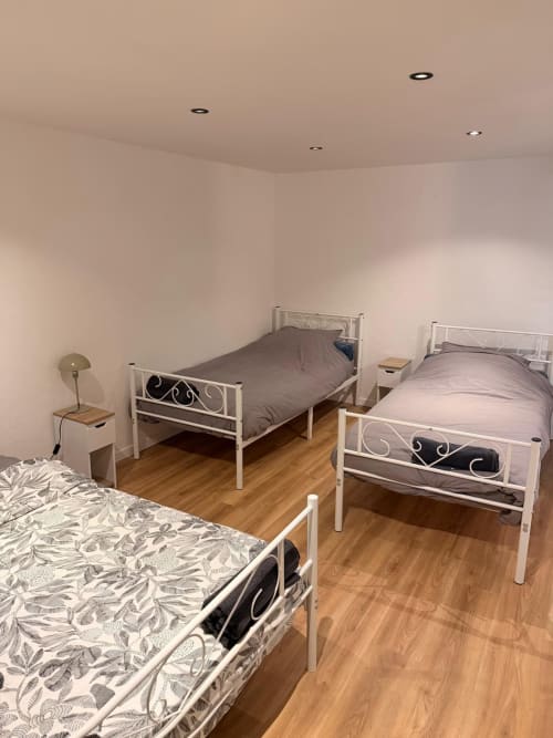 Chambre spacieuse avec trois lits et parquet aux Locations Kawichimmo à Louvres