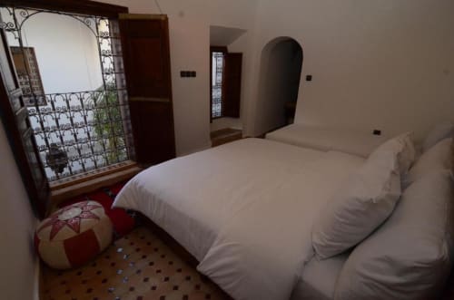 Chambre de l'hôtel Le Cèdre d'Argent à Fès avec lit blanc, miroir ouvragé et décor marocain traditionnel