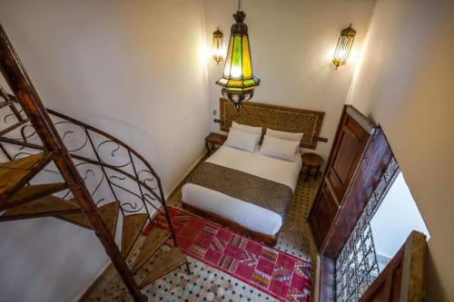 Chambre marocaine à l'hôtel Le Cèdre D'argent à Fès avec luminaire suspendu vert traditionnel, tête de lit ornée et zellige
