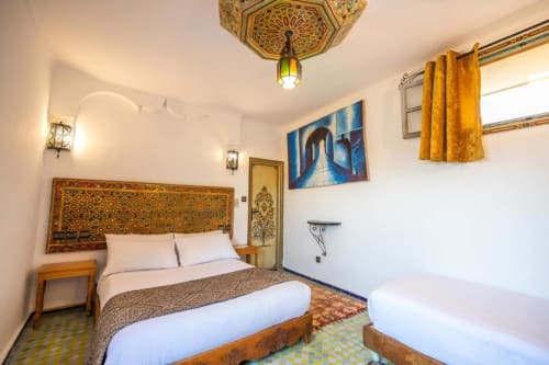 Chambre d'hôtel style marocain au Cèdre D'argent à Fès avec tête de lit dorée ornementée, lits jumeaux et décor traditionnel