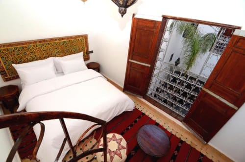 Chambre d'hôtel marocaine à Le Cedre D'argent à Fès avec tête de lit jaune ornée, literie blanche, portes en bois et décor traditionnel