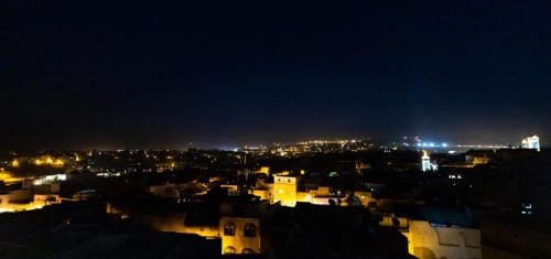Vue aérienne nocturne des toits de Fès avec bâtiments illuminés et lumières de la ville depuis l'hôtel Le Cèdre D'argent
