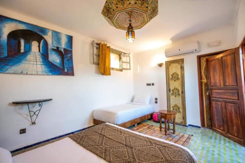 Chambre d'hôtel de style marocain au Cèdre d'Argent à Fès, avec décor traditionnel, luminaire orné et motifs géométriques