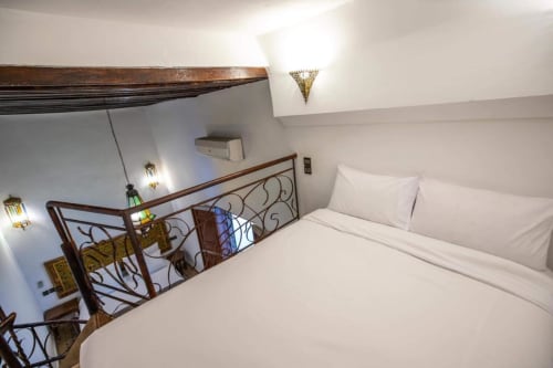 Chambre de luxe au Cèdre d'argent à Fès : lin blanc, balustrade ornementale et éclairage ambiant