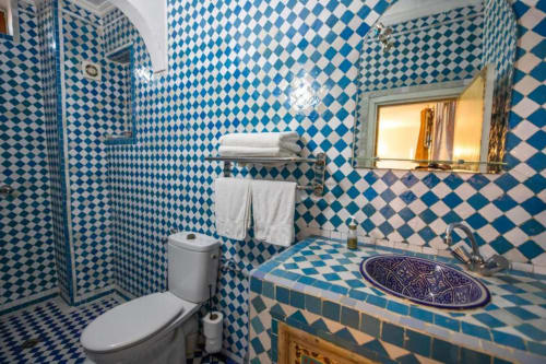 Salle de bain aux carreaux bleus et blancs avec lavabo, toilettes, douche et porte-serviettes à l'hôtel Le Cèdre D'argent à Fès