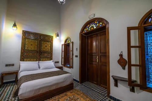 Chambre double de style marocain au Cedre D'argent à Fès avec portes en bois ouvragé, décoration traditionnelle et literie blanche