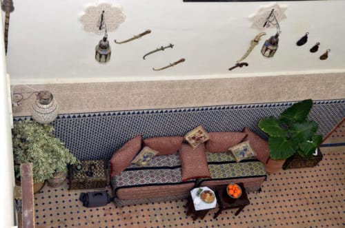 Vue d'ensemble de la chambre double du Riad Dar Tahri à Fès avec canapé-lit bordeaux, coussins décorés, plantes en pot et ambiance marocaine