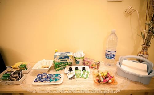 Vassoi di benvenuto Parioli House con articoli da toilette, snack, bottiglia d'acqua e frutta fresca sul tavolo