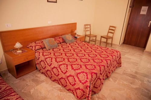 Spaziosa camera da letto a Parioli House B&B Roma con copriletto rosso a motivi, mobili in legno e pavimento piastrellato