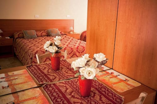 Camera accogliente di Parioli House Rome B&B con arredamento in legno arancione, composizione floreale e tradizionali motivi rossi