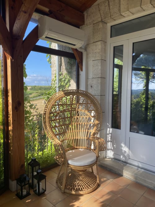 Chaise en rotin tressé sur la terrasse avec vue sur la vallée de Pomport au gîte Le Domaine les Olivoux