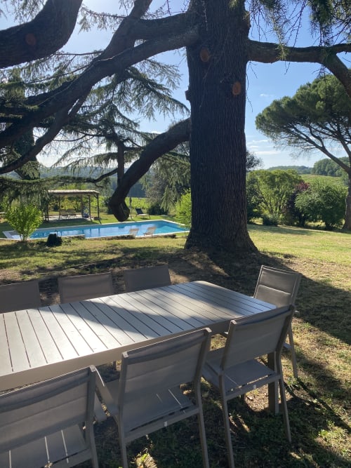 Table de salle à manger en plein air sous un ancien cèdre au Domaine les Olivoux, avec vue sur la piscine et le jardin à Pomport