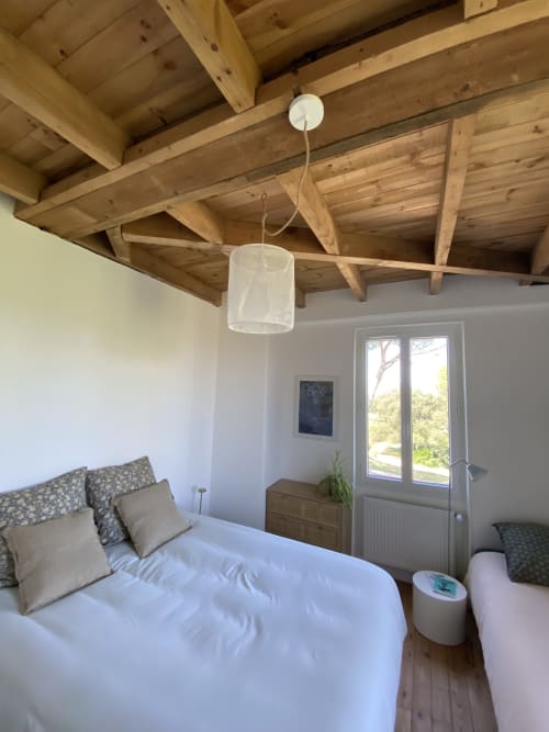 Chambre lumineuse du Domaine les Olivoux avec poutres apparentes, literie blanche et portes donnant sur le jardin