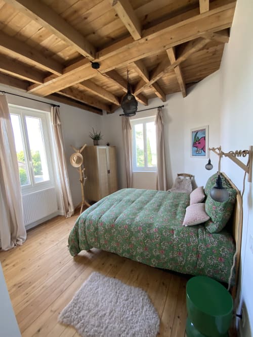 Chambre rustique au Domaine les Olivoux avec poutres apparentes, parure florale verte et vue sur le jardin