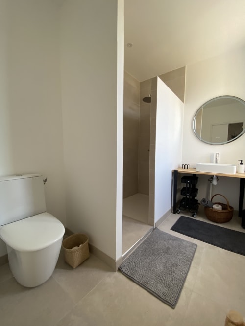 Salle de bains moderne du gîte Le Domaine les Olivoux avec toilettes, douche, lavabo et miroir à Pomport, France