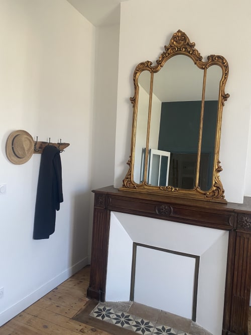 Élégante cheminée avec miroir doré orné et cadre en bois au gîte Le Domaine les Olivoux à Pomport
