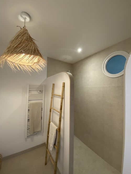 Salle de bain moderne du gîte Le Domaine les Olivoux à Pomport avec lumière naturelle, suspension luminaire tissée et hublot bleu