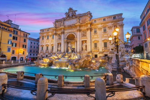 Fontana di Trevi al tramonto a Roma con architettura barocca illuminata e acque turchesi