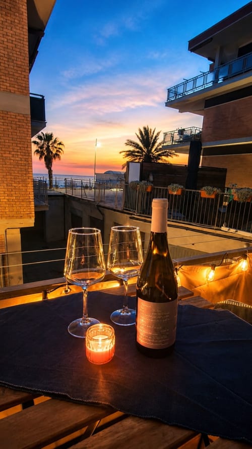 Wine bottle and glasses at sunset on ViOletta rooftop terrace in Rome with sea views