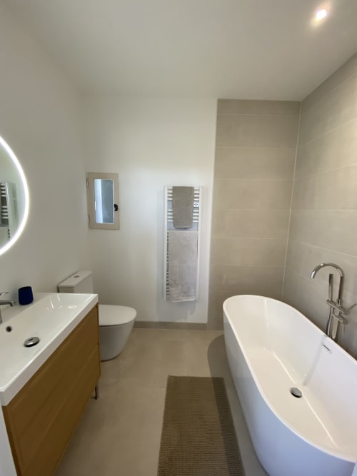 Salle de bain moderne au Domaine les Olivoux avec baignoire îlot, vasque et sèche-serviettes chauffant