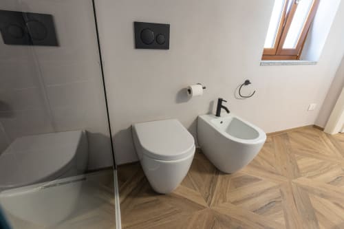 Bagno moderno con wc e bidet bianchi nella suite premium di Miravigne House, con doccia in vetro e rivestimenti in legno