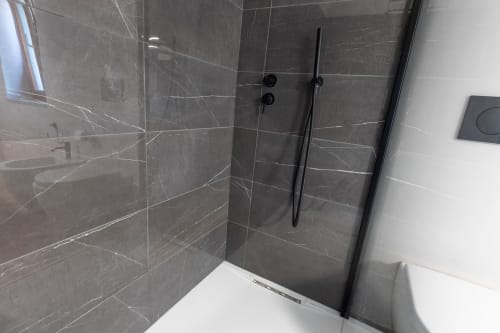 Elegante doccia a filo pavimento con marmo nero e soffione a pioggia nella suite La Camera Premium di Miravigne House, Castagnole delle