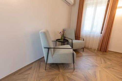 Zona living moderna nella Suite Premium La Camera di Miravigne House con due poltrone rivestite, tavolino laterale e fiori freschi