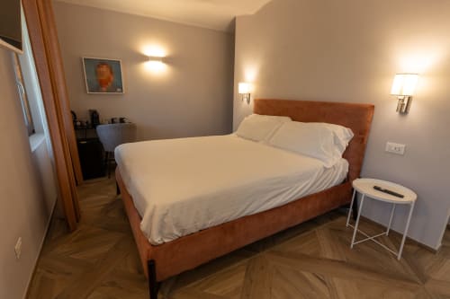 Camera moderna a Miravigne House B&B a Castagnole delle Lanze con letto imbottito arancione, biancheria bianca e illuminazione ambient