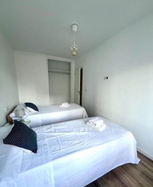 Dormitorio luminoso en apartamento Jacaranda de ROILA360 Alicante con ropa de cama blanca, armario y lámpara colgante
