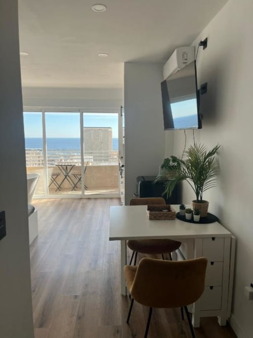 Moderno espacio de trabajo en apartamento con balcón con vistas al mar de Alicante, escritorio, plantas y TV