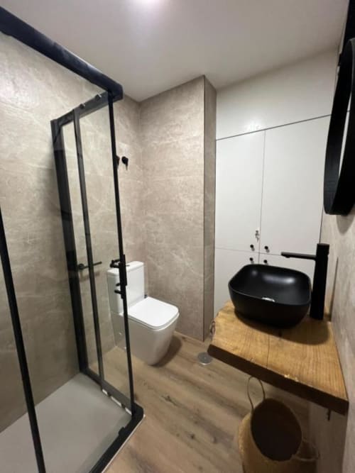 Baño moderno del apartamento ROILA360 Alicante con lavamanos negro, cabina de ducha y inodoro