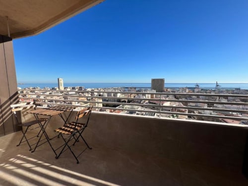 Terraza en azotea con vistas al mar, puerto de Alicante y Mediterráneo, mobiliario exterior y cielo azul despejado