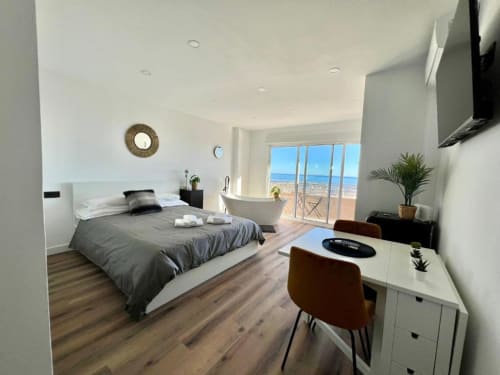 Moderno dormitorio de apartamento frente al mar en Alicante con vistas al mar, bañera, escritorio y terraza balconada