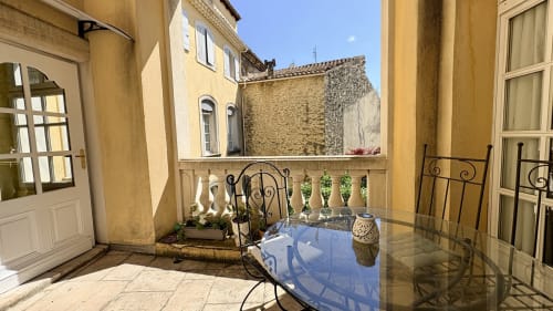 Terrasse Prince d'Orange à Entre vignes et dentelles à Courthézon, avec mobilier de jardin en fer forgé et jardinières