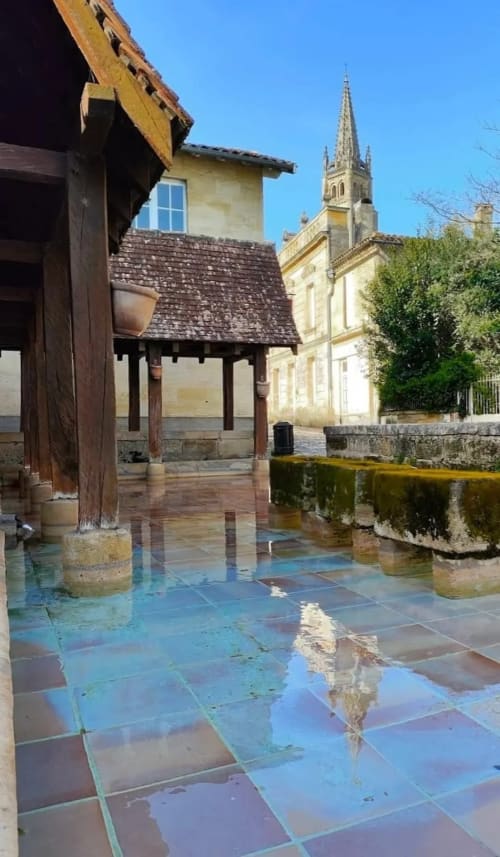 Medieval courtyard at La Maison du Clocher in Saint-Emilion with wet tiles and church spire