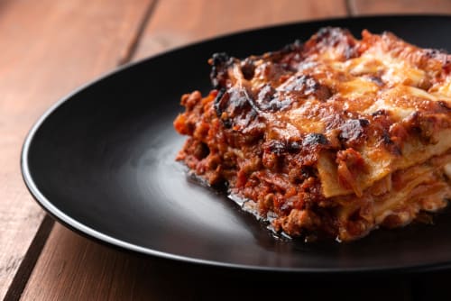 Lasagna alla bolognese stratificata su piatto nero, B&B GATE 10 Fiera Bologna, cucina italiana