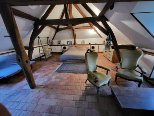 Spacieuse chambre mansardée au Domaine des Oiseaux de Passage avec poutres apparentes, parquet, fauteuils et vue sur le jardin