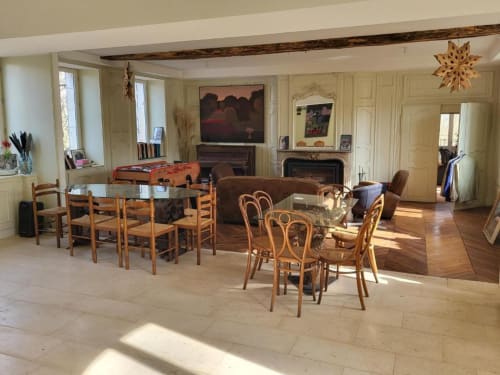Spacieux salon avec tables de salle à manger, chaises en bois, cheminée et vue sur le jardin du Domaine des Oiseaux de Passage