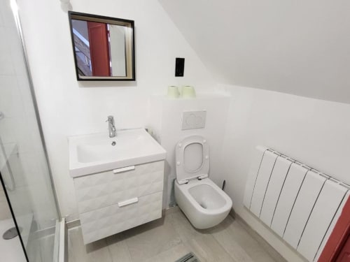 Salle de bains moderne de la Chambre Jean Couy au DOMAINE DES OISEAUX DE PASSAGE avec lavabo blanc, toilettes et radiateur