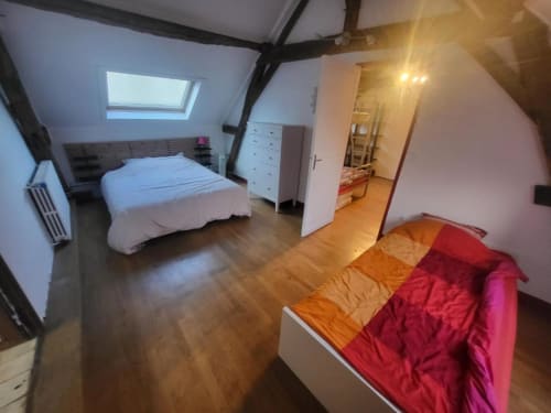 Chambre familiale spacieuse du Domaine des Oiseaux de Passage avec lit, canapé, poutres en bois et lucarne