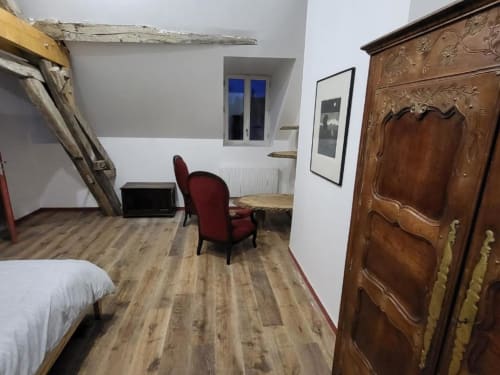 Chambre Jean Couy au DOMAINE DES OISEAUX DE PASSAGE avec parquet, fauteuil rouge et armoire en bois ouvragé