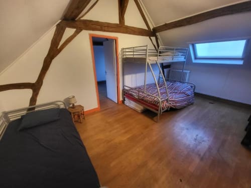 Chambre familiale mansardée avec poutres apparentes, lit superposé, lit simple et fenêtres de toit au Domaine des Oiseaux de Passage