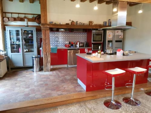 Cuisine moderne rouge avec îlot, appareils électroménagers inox et poutres en bois au cottage Red House