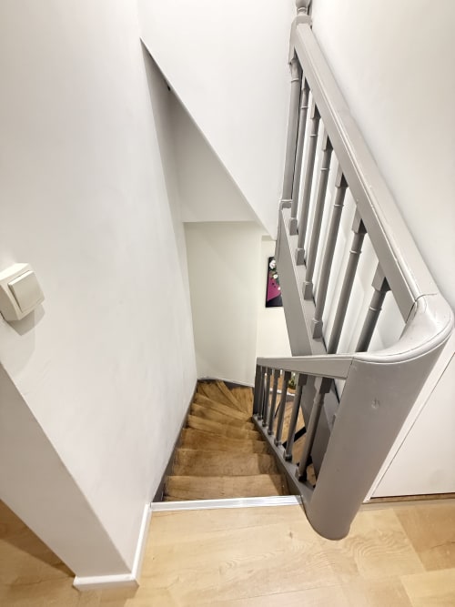 Escalier en spirale aux rampes blanches et marches en bois dans l'appartement Le Quarteau à Metz