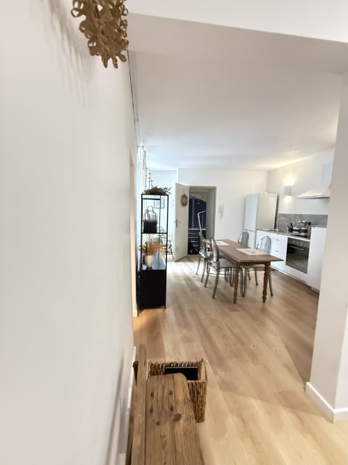 Cuisine-salle à manger moderne dans un appartement messin avec table en bois, électroménagers blancs et entrée du couloir
