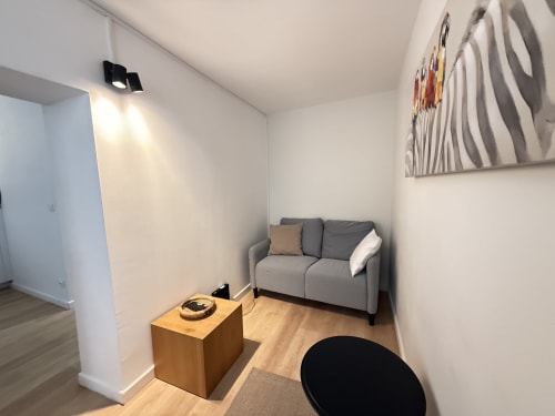 Salon moderne à Metz avec canapé gris, table d'appoint en bois et art mural contemporain