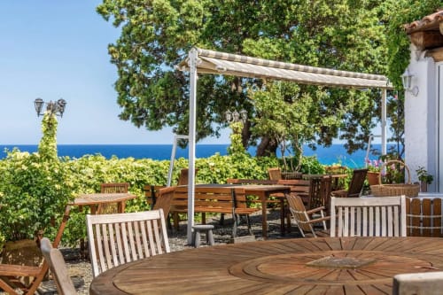 Marina di Bravone outdoor terrace with Mediterranean Sea views, wooden seating, pergola, and lush greenery in Linguizzetta